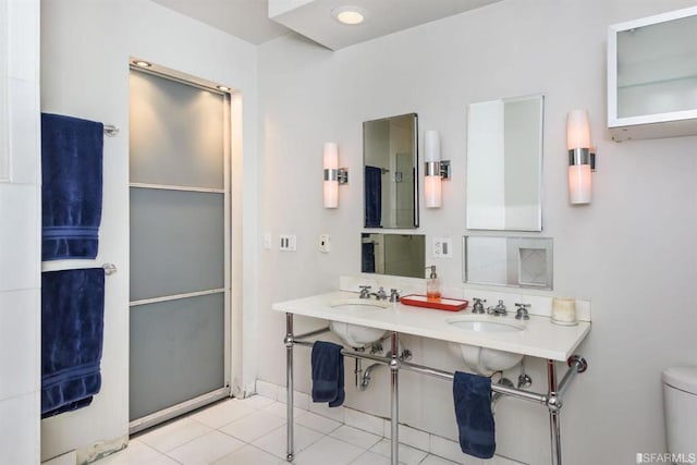 bathroom with toilet, double sink, and tile patterned flooring