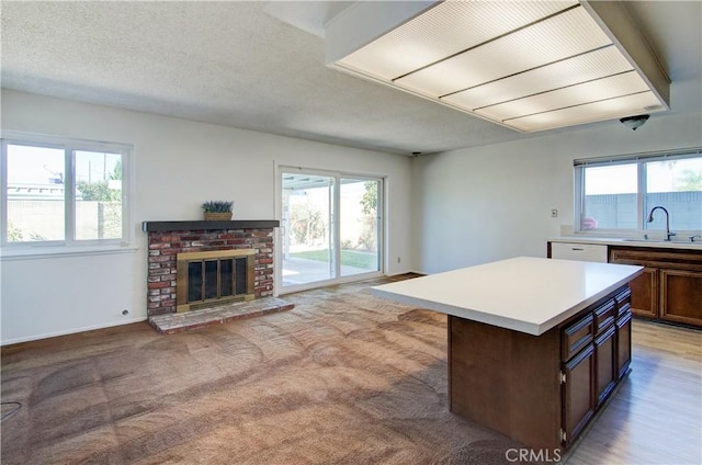 kitchen featuring sink, a kitchen island, a wealth of natural light, and a fireplace