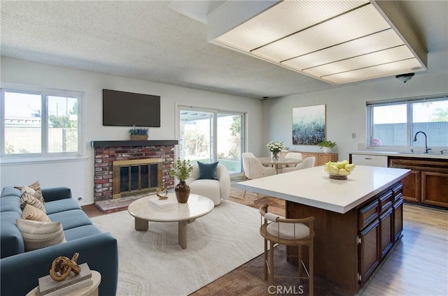 living room featuring sink, a textured ceiling, light hardwood / wood-style floors, and a fireplace