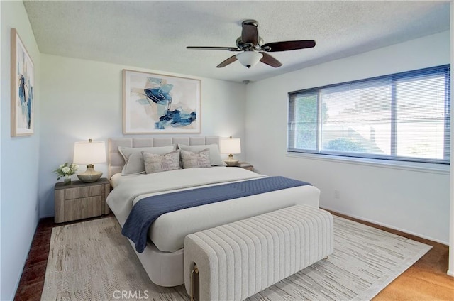 bedroom with hardwood / wood-style floors, a textured ceiling, and ceiling fan