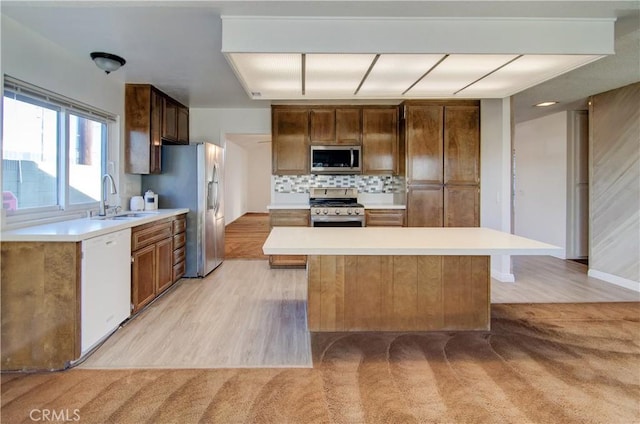 kitchen featuring appliances with stainless steel finishes, decorative backsplash, sink, a kitchen island, and light colored carpet