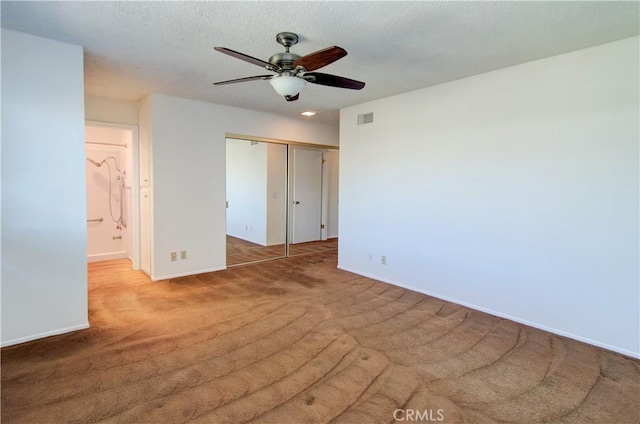 unfurnished bedroom featuring carpet floors, a closet, and ceiling fan