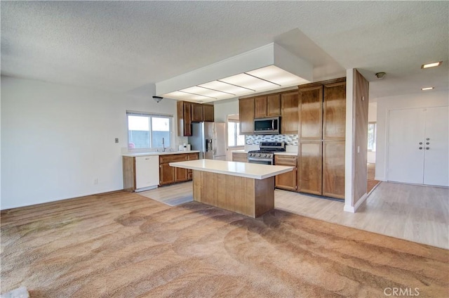 kitchen with light colored carpet, backsplash, appliances with stainless steel finishes, and a center island