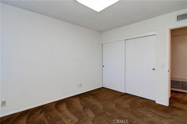 unfurnished bedroom with dark carpet and a closet