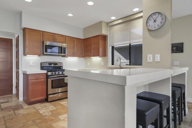 kitchen featuring kitchen peninsula, sink, a breakfast bar area, and stainless steel appliances