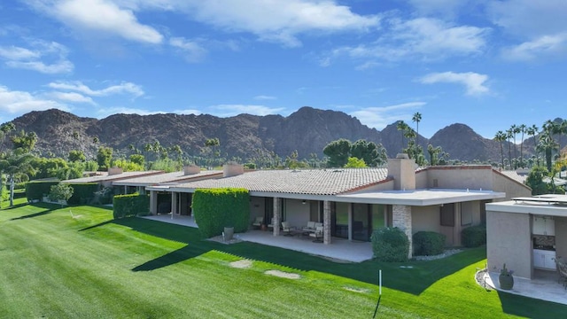 back of property featuring a mountain view, a patio, and a yard