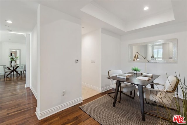 dining space with hardwood / wood-style flooring, ornamental molding, and a tray ceiling