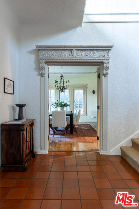 hall featuring an inviting chandelier and dark tile patterned flooring