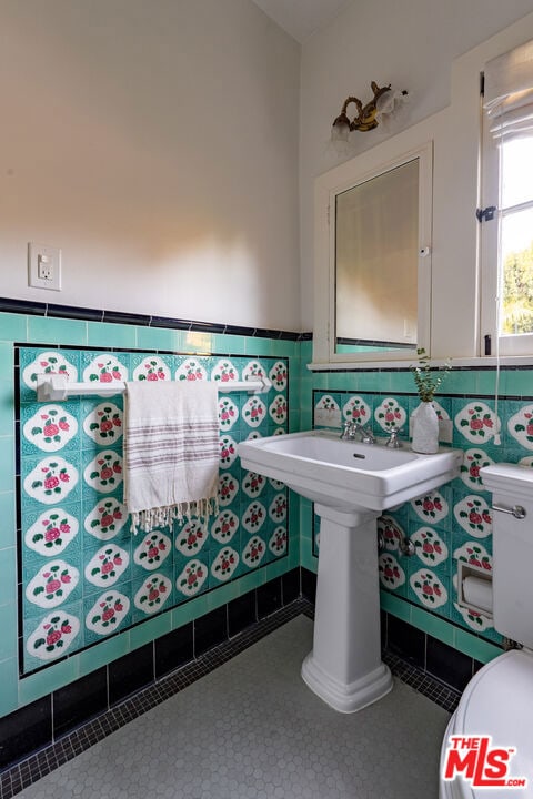 bathroom featuring tile patterned flooring, tile walls, and toilet