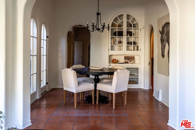 tiled dining room with built in features and a notable chandelier