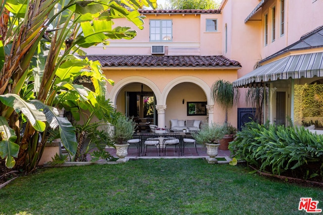 back of house with a yard, a patio area, and a wall unit AC