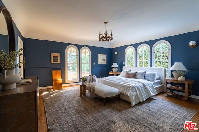 bedroom featuring hardwood / wood-style flooring, access to outside, and a notable chandelier