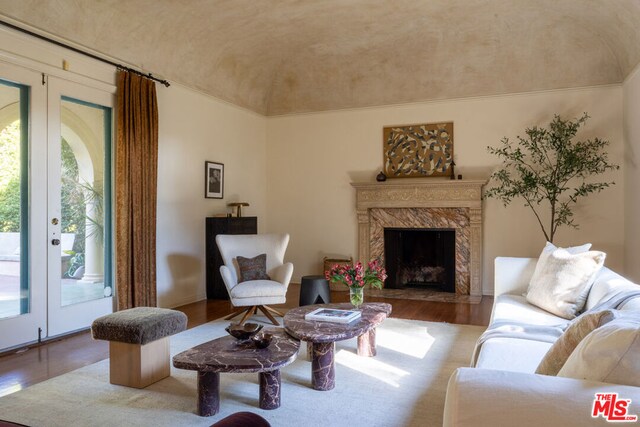 living room with a high end fireplace, wood-type flooring, and french doors