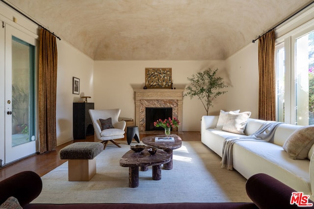 living room with vaulted ceiling, a fireplace, and light hardwood / wood-style flooring