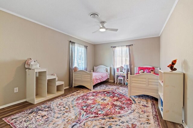 bedroom with crown molding, dark hardwood / wood-style floors, and ceiling fan