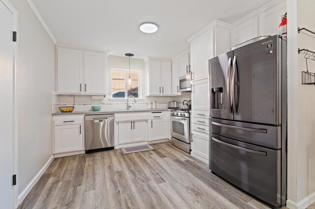 kitchen featuring white cabinetry, decorative backsplash, sink, decorative light fixtures, and stainless steel appliances