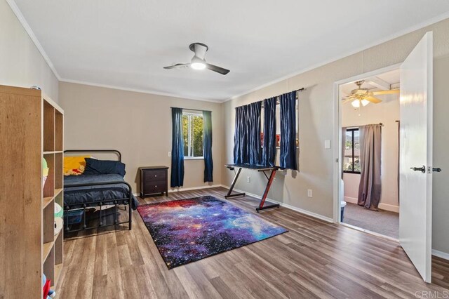 living area featuring hardwood / wood-style flooring, ceiling fan, and crown molding