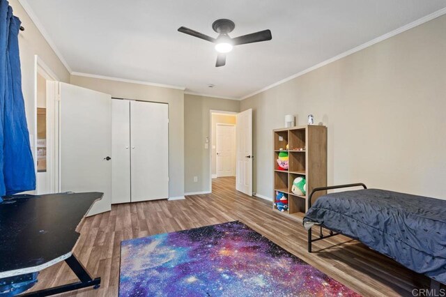 bedroom featuring wood-type flooring, a closet, ceiling fan, and ornamental molding