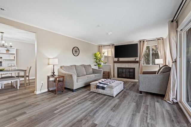 living room with a fireplace, hardwood / wood-style floors, an inviting chandelier, and crown molding