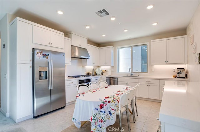 kitchen with sink, light tile patterned floors, white cabinetry, stainless steel appliances, and a center island