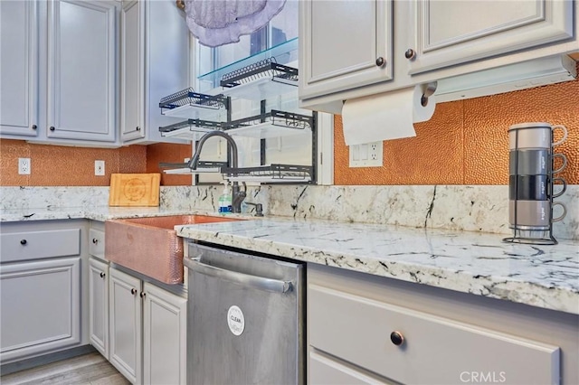 kitchen with dishwasher, sink, and light stone countertops