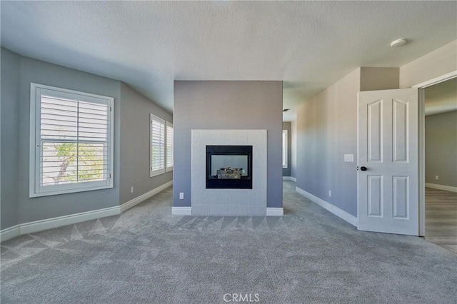 unfurnished living room featuring a tile fireplace, carpet, and a textured ceiling