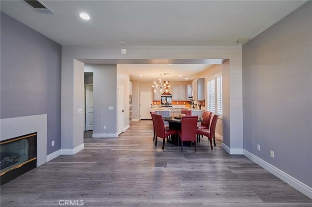 dining room featuring an inviting chandelier, a fireplace, and hardwood / wood-style floors