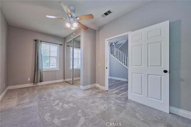 unfurnished bedroom with ceiling fan, a closet, and light carpet