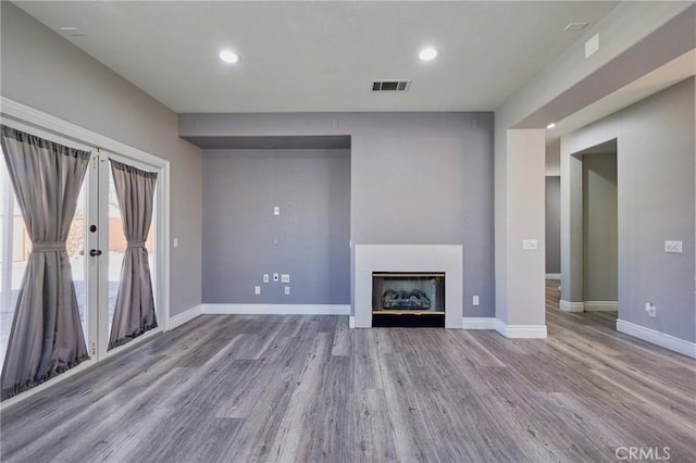 unfurnished living room featuring french doors and light wood-type flooring