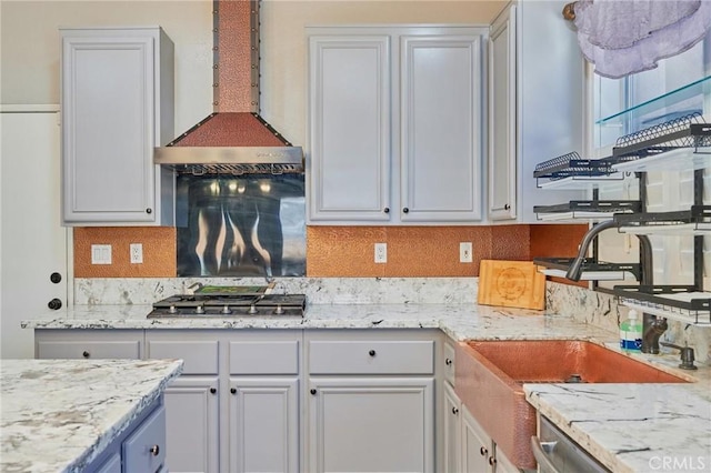 kitchen featuring wall chimney exhaust hood, sink, stainless steel appliances, light stone countertops, and backsplash