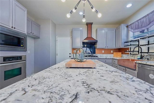 kitchen featuring gray cabinets, appliances with stainless steel finishes, decorative light fixtures, sink, and custom range hood