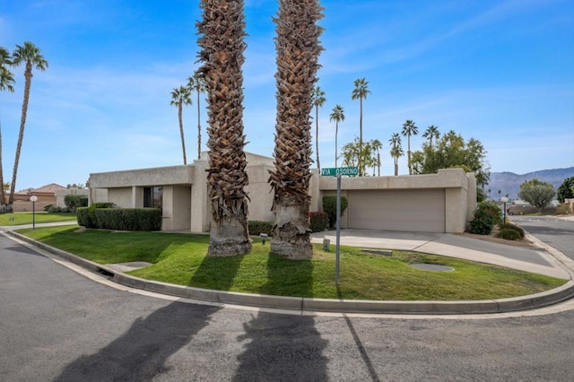 view of front of home with a mountain view, a front lawn, and a garage