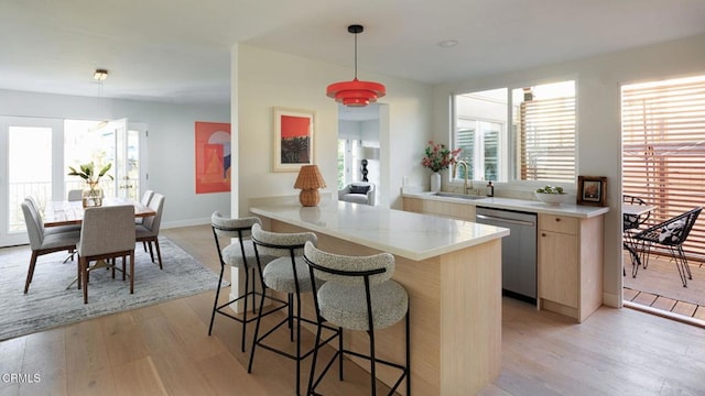 kitchen with pendant lighting, light hardwood / wood-style floors, sink, kitchen peninsula, and stainless steel dishwasher