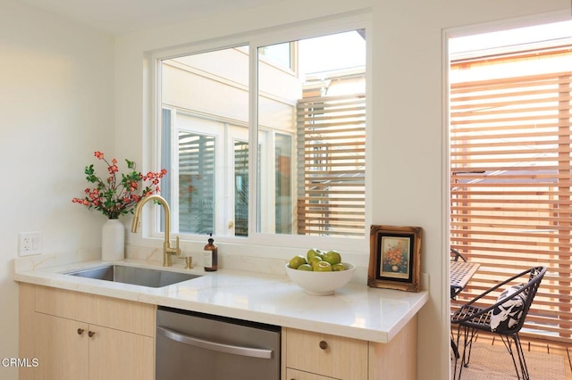 kitchen with sink, stainless steel dishwasher, light brown cabinetry, and light stone counters