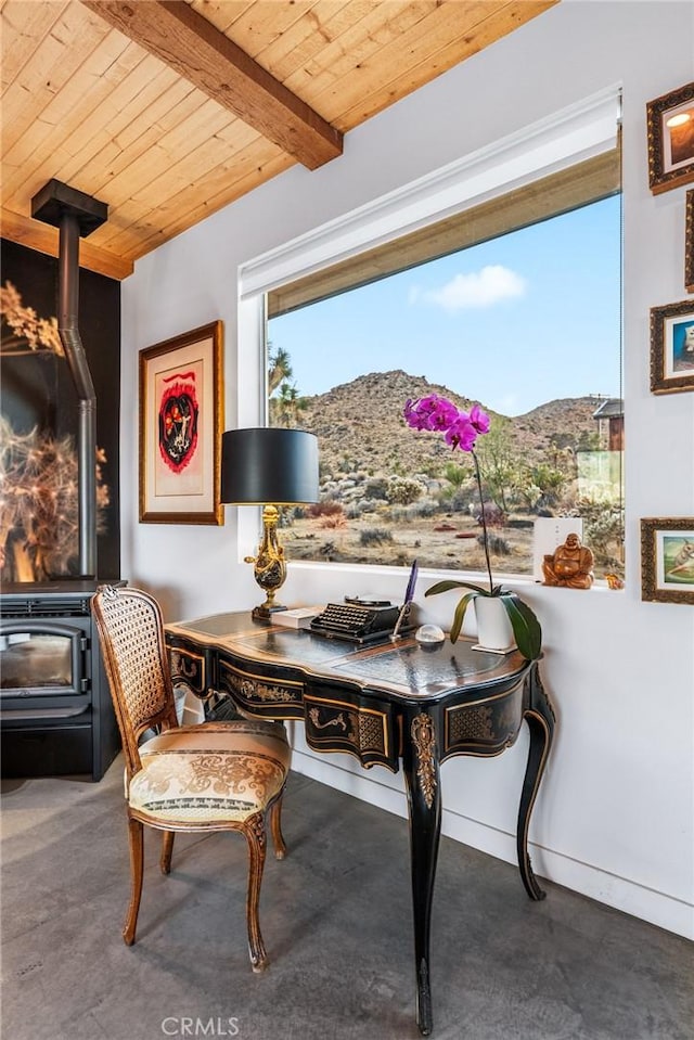 dining space featuring a mountain view, a wood stove, beamed ceiling, and wood ceiling