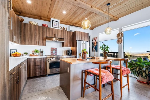 kitchen with decorative light fixtures, butcher block counters, an island with sink, high end appliances, and wooden ceiling