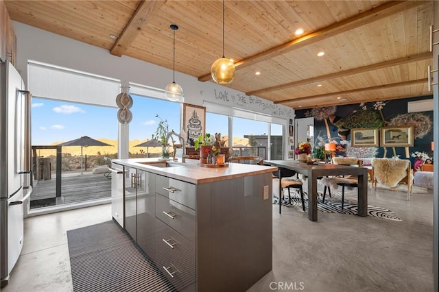 kitchen featuring wood ceiling, a kitchen island with sink, beam ceiling, and stainless steel appliances