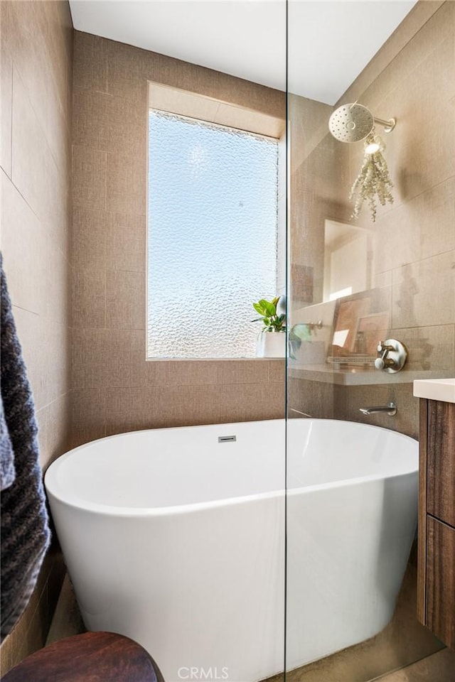 bathroom featuring shower with separate bathtub, vanity, a wealth of natural light, and tile walls