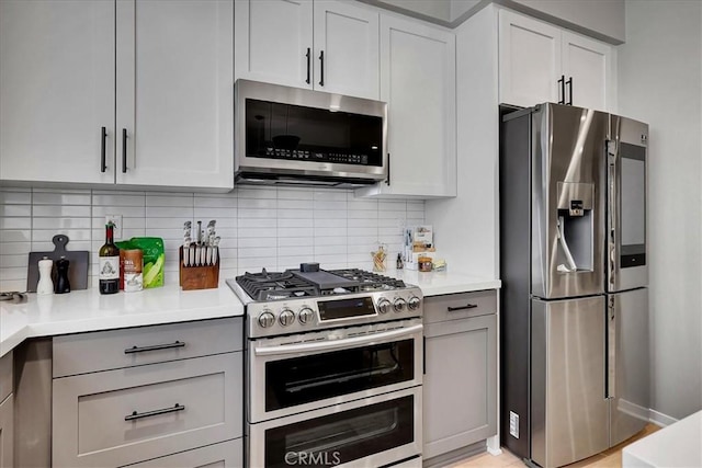 kitchen with gray cabinets, appliances with stainless steel finishes, and decorative backsplash