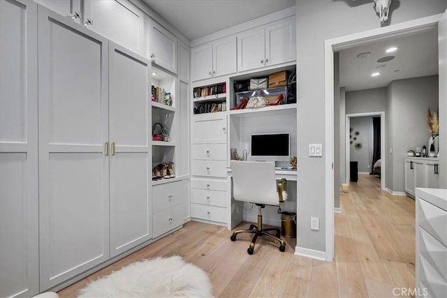 office area with built in shelves and light hardwood / wood-style flooring