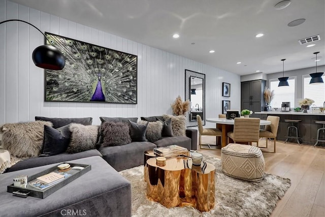 living room with light hardwood / wood-style floors and wood walls