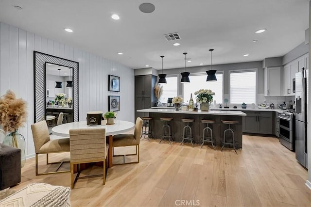 kitchen with gray cabinets, a kitchen island, pendant lighting, a breakfast bar area, and stainless steel appliances