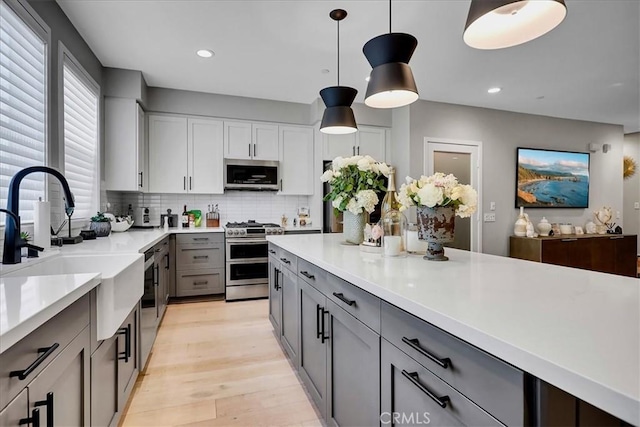 kitchen with sink, gray cabinetry, decorative light fixtures, appliances with stainless steel finishes, and decorative backsplash