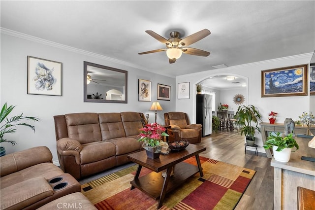 living room featuring dark wood-type flooring, ceiling fan, and ornamental molding