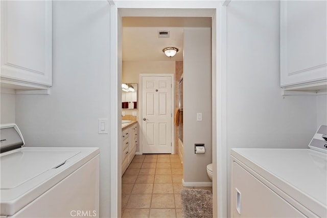 washroom with light tile patterned floors, cabinets, and washer and clothes dryer