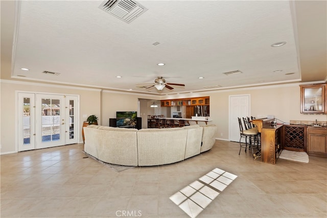 living room featuring sink, ceiling fan, a raised ceiling, and crown molding