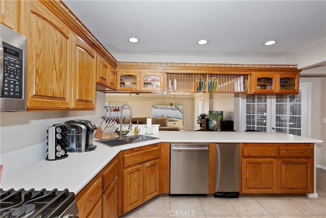 kitchen with sink, kitchen peninsula, light tile patterned floors, and stainless steel appliances