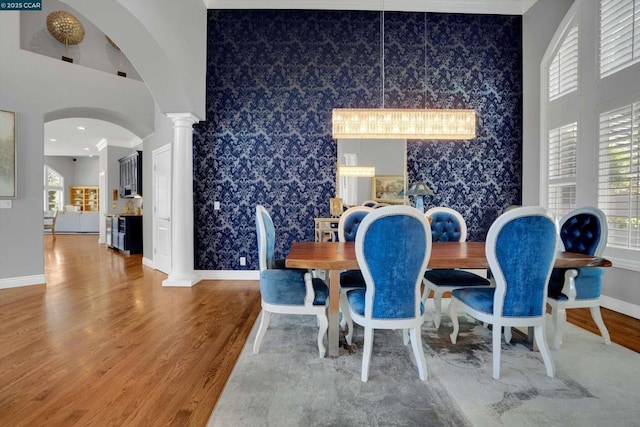 dining room with hardwood / wood-style floors, decorative columns, and ornamental molding