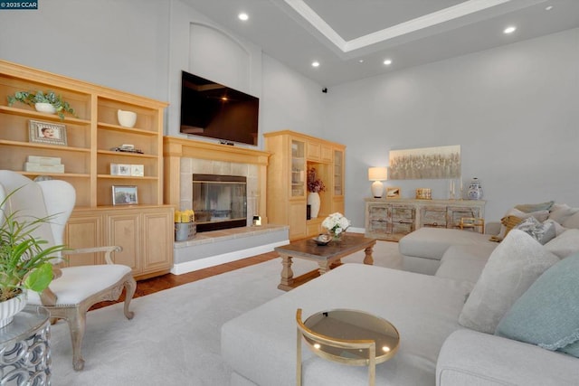 living room with hardwood / wood-style floors, a towering ceiling, built in shelves, a fireplace, and ornamental molding