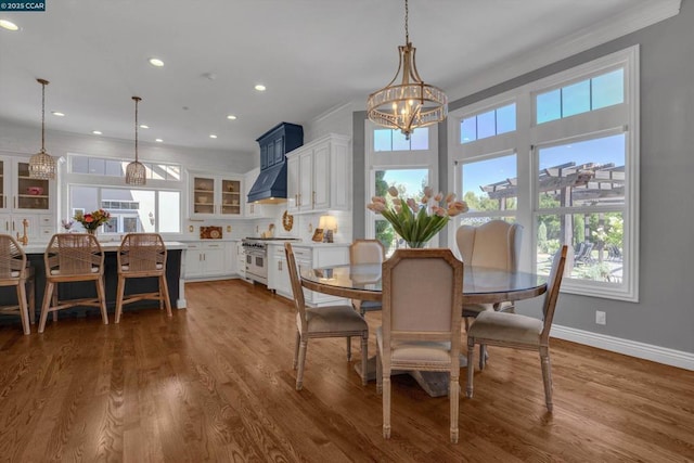 dining area featuring wood-type flooring, ornamental molding, and an inviting chandelier